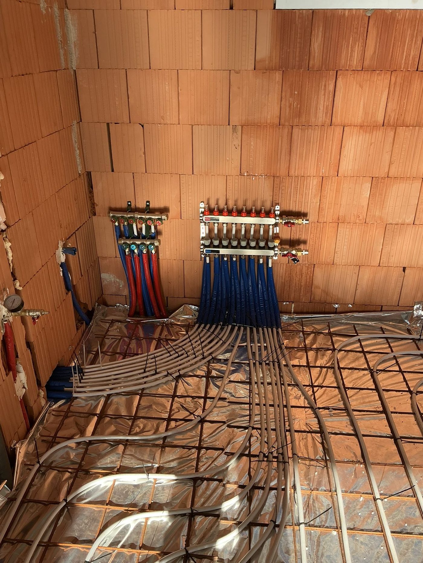 Padlófűtés osztók téglafal előtt